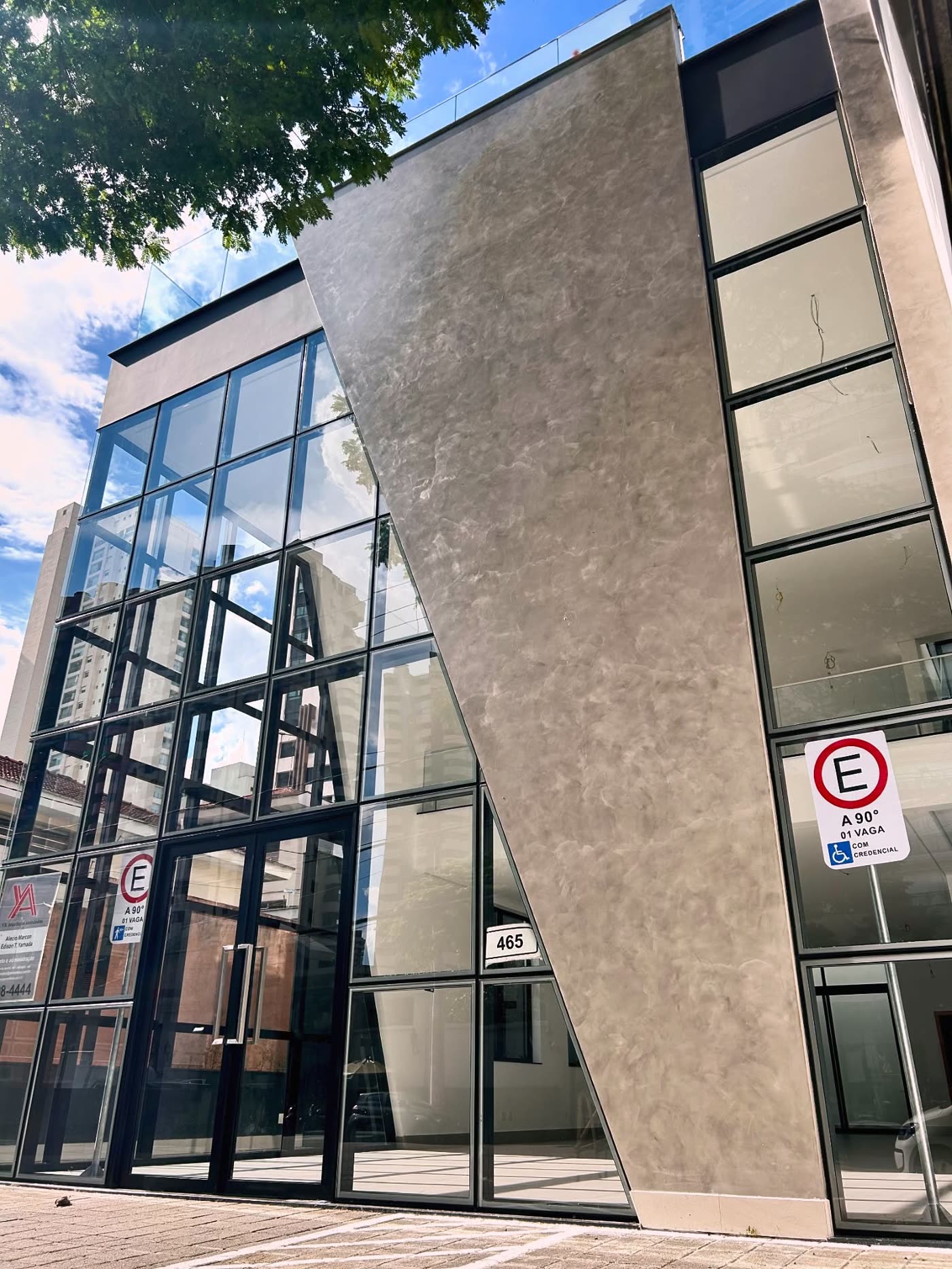 Fachada de edifício projetado e executado pela YA, com uma lâmina de concreto em diagonal ao lado da caixa de vidro